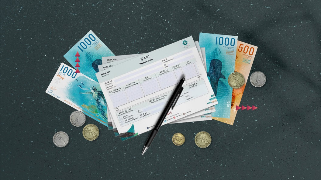 A scatter of MVR one and MVR two coins with notes of MVR 1,000 and MVR 500 positioned beneath MIRA's tax payment forms