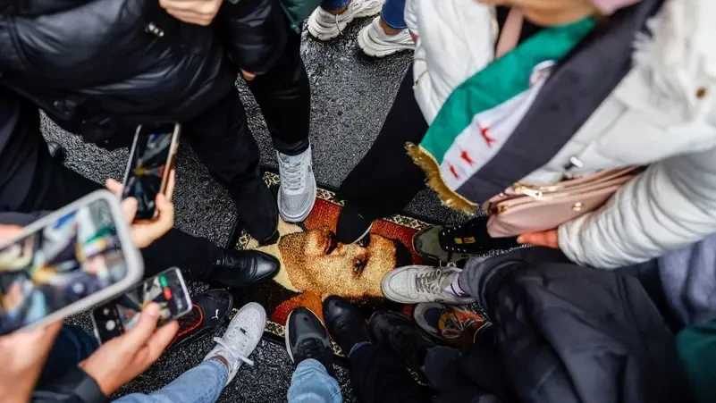 ކާޕެޓެއްގައި ޖަހާފައިވާ އަސަދުގެ ތަސްވީރުގެ މައްޗަށް ބަޔަކު ފައިން އަރައިގެން