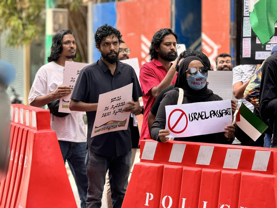 އިޒްރޭލް ޕާސްޕޯޓް މަނާކުރުމަށް ގޮވާލާ ކުރި މުޒާހަރާގެ ތެރެއިން - އެއްވުމަށް ދިޔަ ފަރާތްތަކުން އިޒްރޭލަށް އެެހީތެރިވެދޭ ފަރާތްތަކާއި، އުފެއްދުންތައްވެސް ރާއްޖެއަށް އެތެރެވުން މަނާކުރުމަށް ގޮވާލާ ލިޔެފައި ބޯޑްތައް ހިފައިގެން އަޑު އުފުލާފަ - ފޮޓޯ: ޙުސައިން މަޚްތޫމް