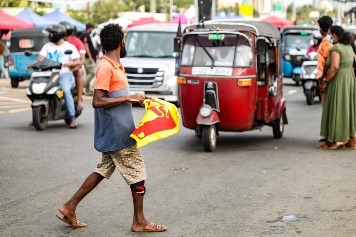ސްރީލަންކާގެ އިގުތިސާދީ ހާލަތު ގޯސްވެ ކުރިމަތިވެފައިވާ ގޮންޖެހުންތަކާ ގުޅިގެން ކުރަމުންދާ މުޒާހަރާގައި މީހަކު އެ ގަމުގެ ދިދަ ހިފައިގެން މަގުމަތީގައި - ފޮޓޯ: ރާއްޖެއެމްވީ 