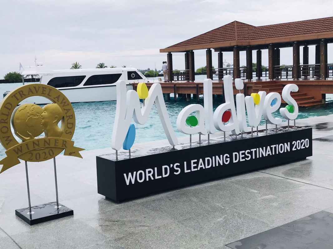 A large sign reading "Maldives" with colorful accents on some of the letters, near the jetty area of VIA