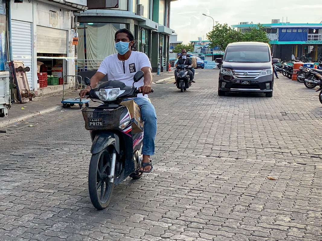 ކޮވިޑް19 ކޮންޓްރޯލްކުރަން ރައްކާތެރިކަމުގެ ފިޔަވަޅެއްގެ ގޮތުން މީހަކު މާސްކު އަޅައިގެން ސައިކަލުގައި ދުއްވާފައި ދަނީ -  ފިހާރަ ފަދަ ތަންތަނާއި މީހުން ގިނަ ތަންތަނަށް ދާއިރު ވެސް މާސްކެއް އަޅައިގެން ދިޔުން ވަރަށް މުހިއްމު - ފޮޓޯ: ރާއްޖެއެމްވީ