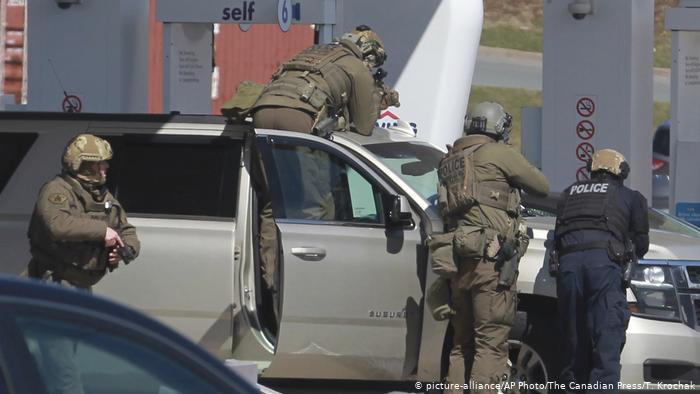 Royal Canadian Mounted Police officers surround a suspect at a gas station in Enfield, Nova Scotia