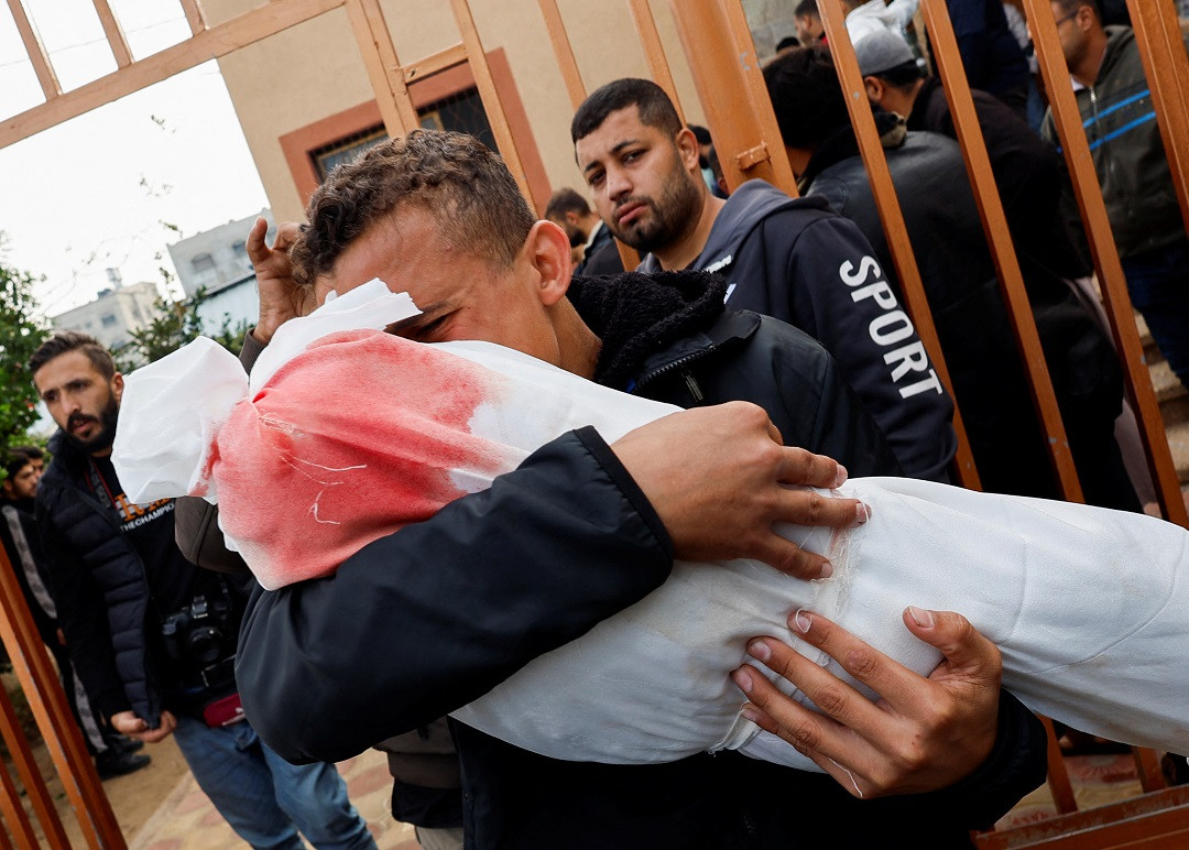 އިސްރާއީލުން ޣައްޒާއަށް ދިން ހަމަލާއެއްގައި ޝަހީދުވެފައިވާ ތުއްތު ކުއްޖެއްގެ ހަށިގަނޑު އުރާލައިގެން ހުރި ފަލަސްތީންގެ ފިރިހެނެއް - ފޮޓޯ: ރޮއިޓަރސް