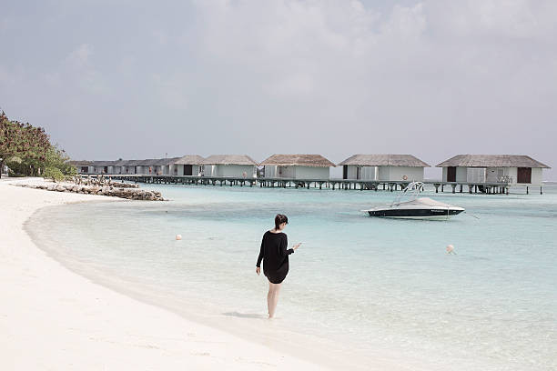 A woman walking along the sandy beach of a resort in the Maldives