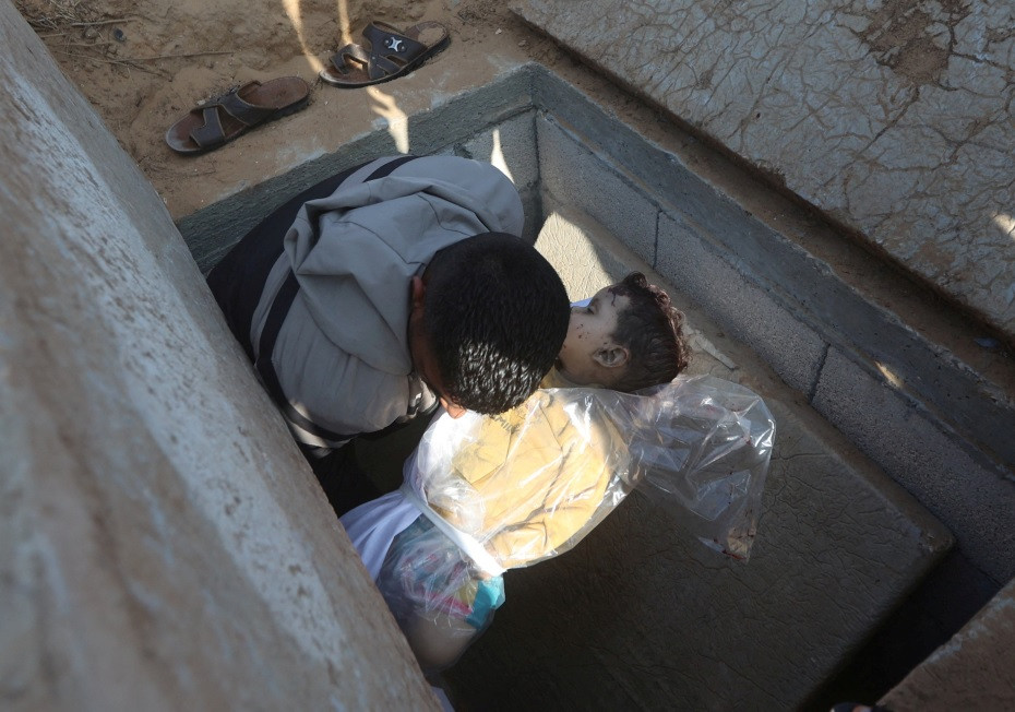 އިސްރާއީލުން ވަށާލާފައިވާ ޣައްޒާއަށް ޖެހިޖެހިގެން ވައިގެމަގުން ދިން ވަރުގަދަ ހަމަލާތަކުގައި ޝަހީދުކޮށްލި ކުޑަ ކުއްޖަކު ވަޅުލާ މަންޒަރު - ފޮޓޯ: ރޮއިޓާސް