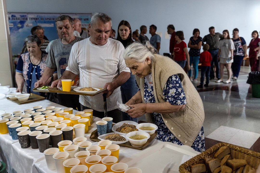 ޔޫކްރެއިން ބޯޑަރާ ކައިރި ހިސާބުތަކުގައި އުޅޭ މީހުން ބަދަލުކުރުމަށް ގާއިމުކުރި ވަގުތީ ހިޔާއެއްގައި މީހުން ކެއުމަށް ކިއުގައި - ފޮޓޯ: ރޮއިޓަރސް