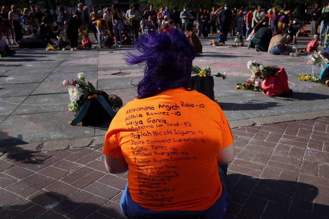 އެމެރިކާގެ ޓެކްސަސްގެ ރޮބް އެލެމެންޓްރީ ސްކޫލްގައި ދިން ބަޑީގެ ހަމަލާގައި މަރުވި ކުދިންނާއި ޓީޗަރުންގެ ނަންތައް ލިޔެފައިވާ ޓީޝަރޓެއް ލައިގެން އިން މީހެއް -- ފޮޓޯ: ރޮއިޓަރސް