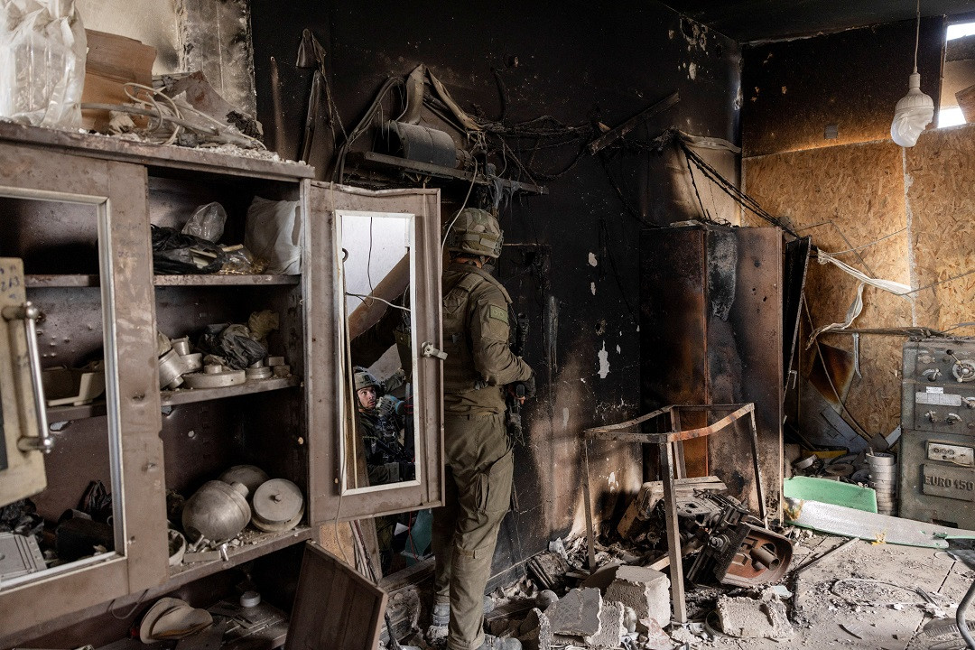 ޣައްޒާއަށް އަރައިގެން އުޅޭ އިސްރާއީލުގެ އަސްކަރީ އޮފިސަރަކު، އެމީހުންގެ ބޮމުގެ ހަމަލާތަކުގައި ގެއްލުންލިބިފައިވާ ގެއެއްގެ ތެރޭގައި - ފޮޓޯ: ރޮއިޓަރސް