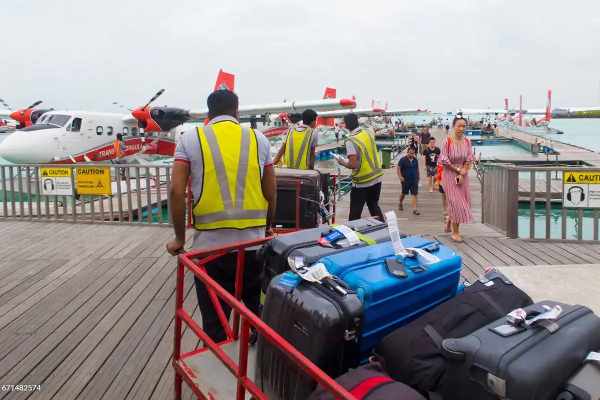 މާލޭ އިންޓަނޭޝަނަލް އެއާޕޯޓުގެ ސީޑްރޯމްގައި ޓްރާންސް މޯލްޑިވިއަން އެއާވޭސްގެ ސީޕްލޭންތަކަށް ފަތުރުވެރިންގެ ލަގެޖު ޕޯޓަރުން ގެންދަނީ