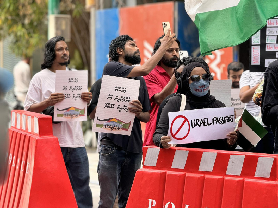 އިޒްރޭލް ޕާސްޕޯޓް މަނާކުރުމަށް ގޮވާލާ ކުރި މުޒާހަރާގެ ތެރެއިން - އެއްވުމަށް ދިޔަ ފަރާތްތަކުން ވަނީ އިޒްރޭލަށް އެެހީތެރިވެދޭ ފަރާތްތަކާއި، އުފެއްދުންތައްވެސް ރާއްޖެއަށް އެތެރެވުން މަނާކުރުމަށް ގޮވާލާ ލިޔެފައި ބޯޑްތައް ހިފައިގެން އަޑު އުފުލާފަ - ފޮޓޯ: ޙުސައިން މަޚްތޫމް