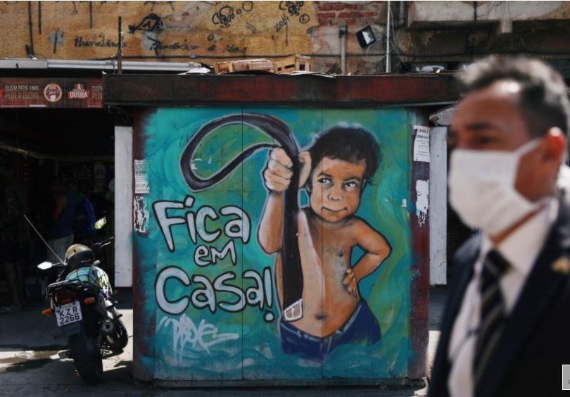 ބްރެޒިލްގައި \"ސްޓޭ އެޓް ހޯމް\" ޖަހާފައިވާ ފާރެއްގެ ކައިރިން މީހަކު މާސްކު އަޅައިގެން ހިނގާފައިދަނީ