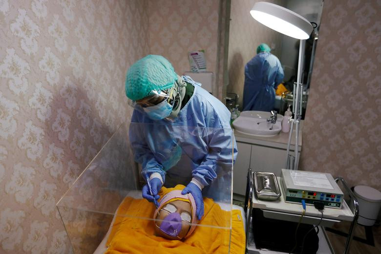 ކޮރޯނާ ވައިރަސްއާއެކު ދިރިއުޅުން - އިންޑޮނޭޝިއާގެ ޖަކާޓާގެ ހަމުގެ ހާއްސަ ޑޮކްޓަރެއް އޭނާގެ ޕޭޝަންޓެއްގެ މޫނުގެ ހަންގަނޑު ރީތި ކުރުމުގެ މަސައްކަތް ކުރަމުންދަނީ، ލޮކްޑައުންއަށް ލުއިތަކެއް ދިނުމާއެކު އެގައުމުގައި ވަނީ އަމަލުކުރަންޖެހޭ ހާއްސަ ފިޔަވަޅުތަކެއް އެކުަލަވާލާފައި - ފޮޓޯ: ރޮއިޓަރސް